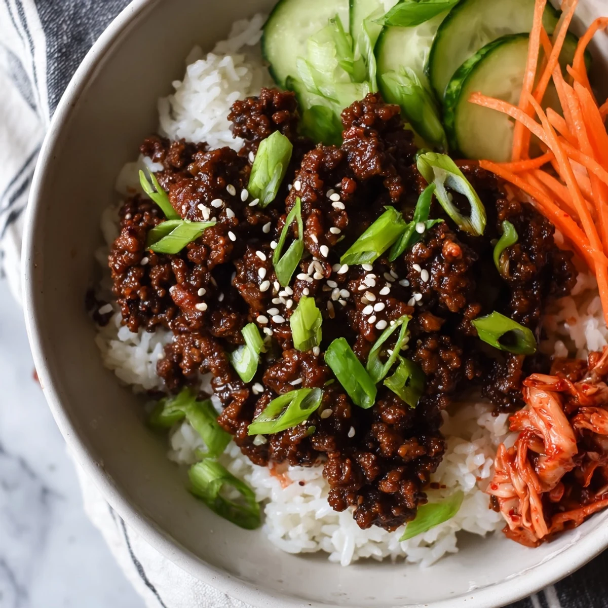 Warm Korean ground beef bowl topped with sesame seeds green onions and julienned carrots