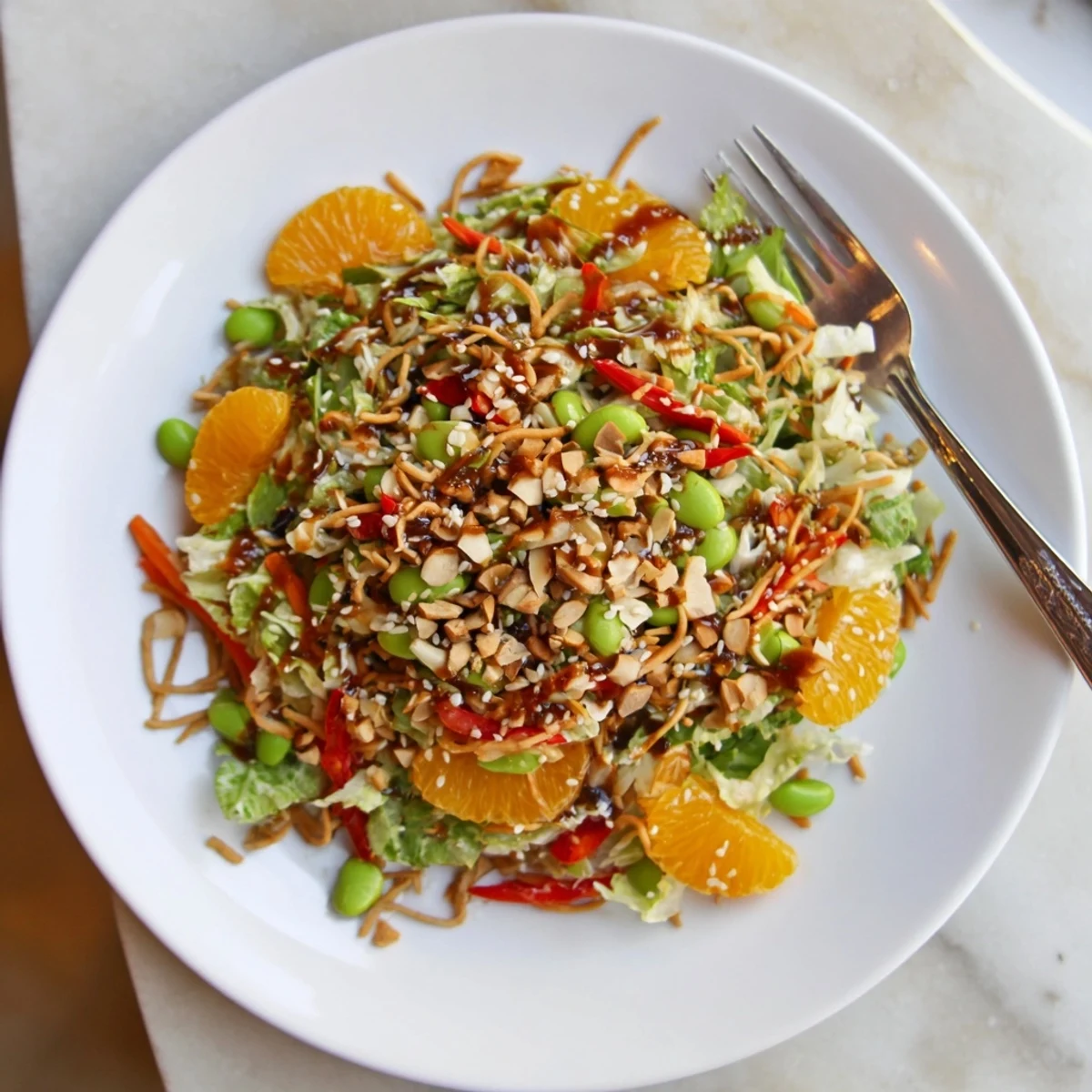 Bright Mandarin Sesame Crunch Salad topped with golden noodles and toasted almonds