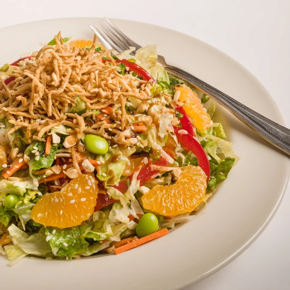 Colorful Mandarin Sesame Crunch Salad glistening with tangy sesame ginger dressing in a wooden bowl