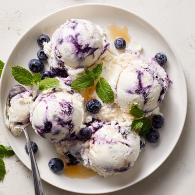 Blueberry Cottage Cheese Ice Cream served in a dish, topped with honey drizzle and mint garnish.