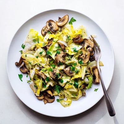 Steaming Vegetarian Cabbage Mushroom Sauté in a skillet, featuring tender green cabbage and earthy mushrooms with a hint of garlic.