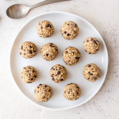 Mint chocolate chip protein balls stacked on a wooden board, suggesting a cool and refreshing post-workout snack.