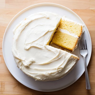 Freshly baked Perfect Vanilla Cake layers with smooth vanilla buttercream, shown on a rustic wooden table.