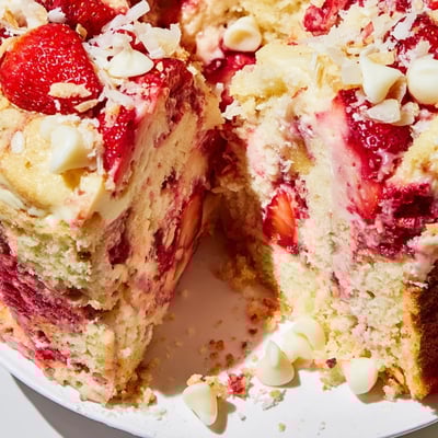 A close up view of a gooey Strawberry Earthquake Cake showing fresh diced strawberries and moist red velvet crumb.