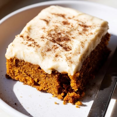 Creamy frosted pumpkin bars cut into neat squares dusted with fragrant cinnamon