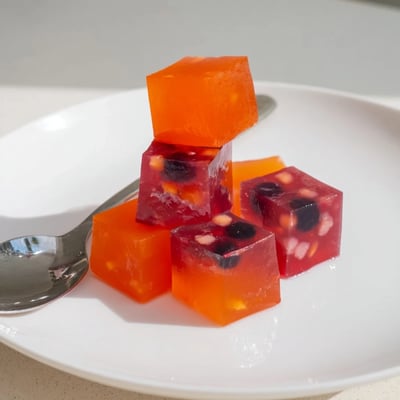 Bright homemade collagen fruit jellies dotted with fresh berries in silicone molds